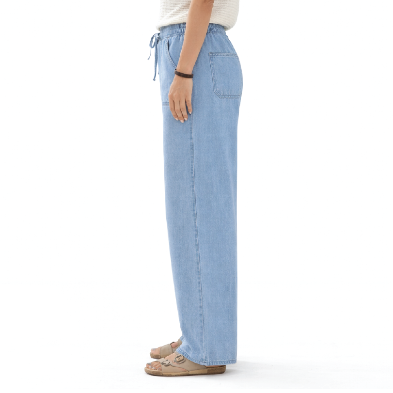 A person shown from the waist down wearing light blue wide-leg denim pants with a drawstring waistband, standing against a plain white background.